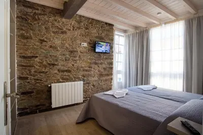 a bedroom with a bed and a brick wall at Pensión Domus Gallery in Arzúa
