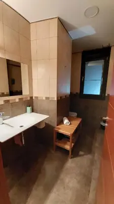 a bathroom with a sink and a mirror and a bench at Alojamientos Marel Sanabria in Villarino de Sanabria