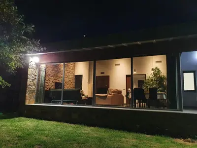 a living room with glass windows at night at Alojamientos Marel Sanabria in Villarino de Sanabria