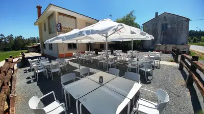 a group of tables and chairs with an umbrella at Casa Tia Teresa in Salceda