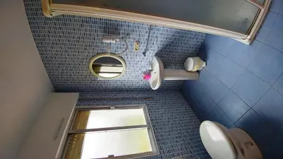 a blue tiled bathroom with a window and a toilet at Casa Tia Teresa in Salceda