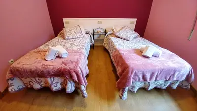 two beds in a room with pink walls at Casa Tia Teresa in Salceda