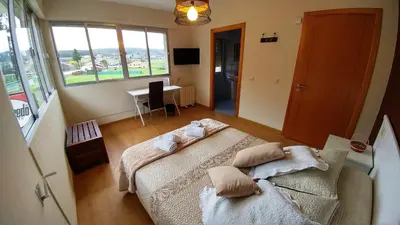a bedroom with two beds and a desk and a window at Casa Tia Teresa in Salceda