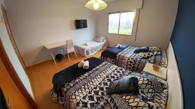 a room with three beds and a table and a desk at Casa Tia Teresa in Salceda