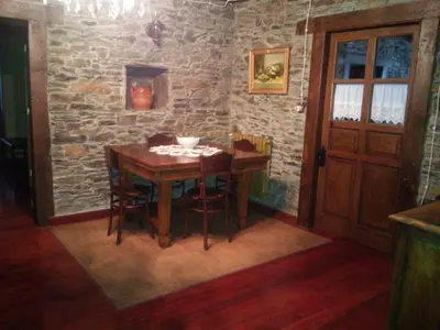 a dining room with a wooden table and a stone wall at Casa Colason in El Otero