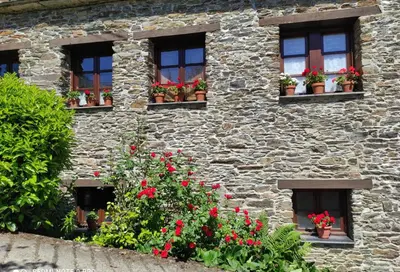 a stone building with red flowers in the windows at Casa Colason in El Otero
