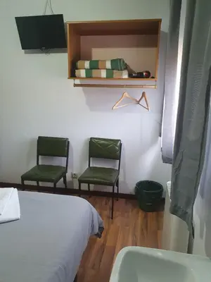 a bedroom with two green chairs and a bed and a sink at A Concha in Lavacolla