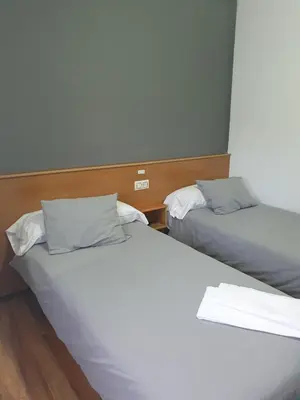two beds in a room with white sheets and pillows at A Concha in Lavacolla