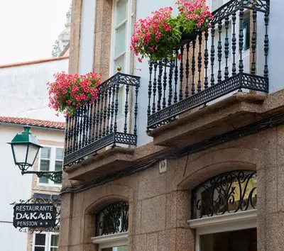 a building with two balconies with flowers on it at Pensión O Códice by Moradas Nieto in Santiago de Compostela