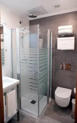 a bathroom with a glass shower with a toilet at Pensión O Códice by Moradas Nieto in Santiago de Compostela