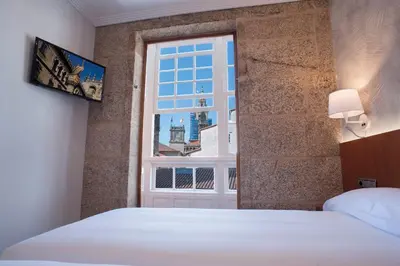 a bedroom with a bed and a window at Pensión O Códice by Moradas Nieto in Santiago de Compostela