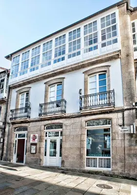 an old brick building with windows and balconies at Pensión O Códice by Moradas Nieto in Santiago de Compostela