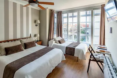 a bedroom with two beds and a large window at A Morada do Cigarron in Verín