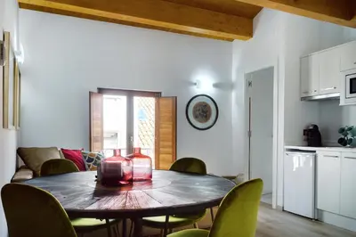 a table in a living room with chairs and a kitchen at Numa Rúa Travesa in Santiago de Compostela