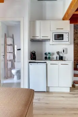 a kitchen with white cabinets and a microwave at Numa Rúa Travesa in Santiago de Compostela