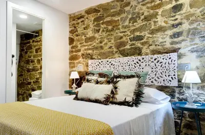 a bedroom with a bed with a stone wall at Numa Rúa Travesa in Santiago de Compostela