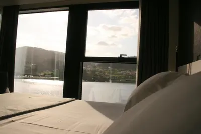 a bedroom with a large window looking out at the water at Hotel U Viveiro in Viveiro