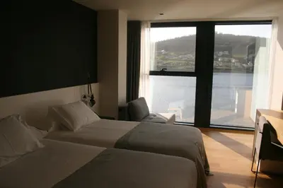 a hotel room with two beds and a large window at Hotel U Viveiro in Viveiro