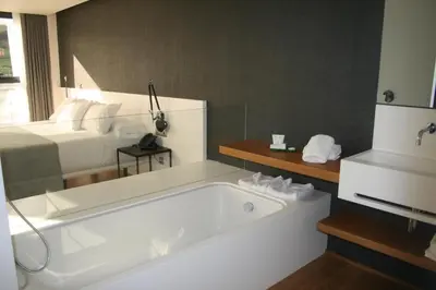 a white bath tub in a room with a bed at Hotel U Viveiro in Viveiro