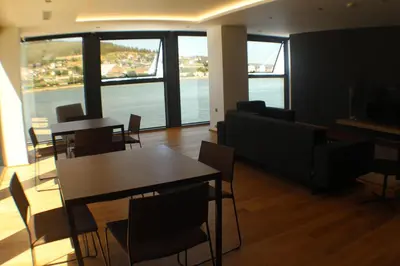 a dining room with tables and chairs and a large window at Hotel U Viveiro in Viveiro