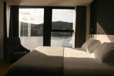 a bedroom with a bed and a large window at Hotel U Viveiro in Viveiro