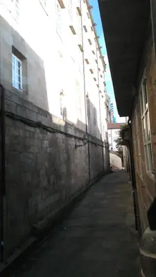an alley with a brick wall next to a building at PICO SACRO I HOSTAL-PENSION Santiago de Compostela in Santiago de Compostela