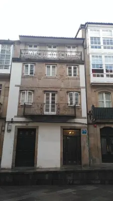a tall brick building with windows and balconies at PICO SACRO I HOSTAL-PENSION Santiago de Compostela in Santiago de Compostela