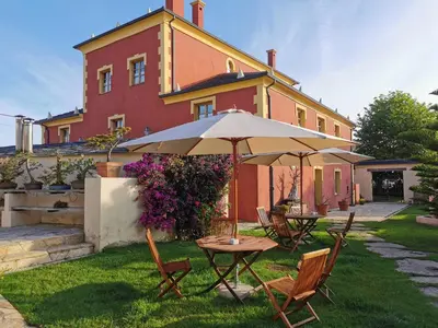 a table and chairs with an umbrella in front of a house at Casa do Merlo in Barreiros