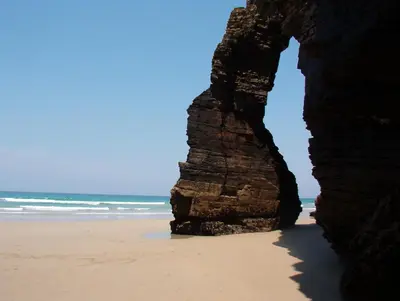a view of the beach through a rock formation at Casa do Merlo in Barreiros