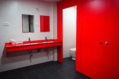 a red bathroom with two sinks and a toilet at Albergue Mirás in Sigüeiro