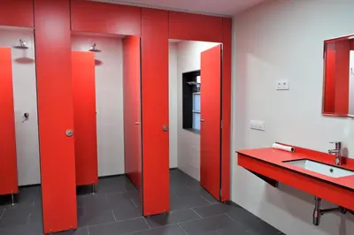 a bathroom with red stall doors and a sink at Albergue Mirás in Sigüeiro