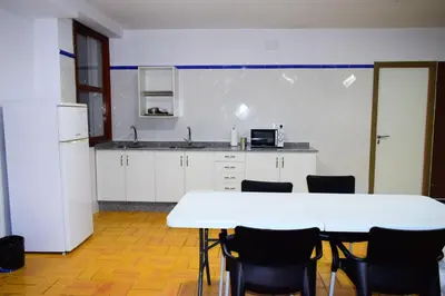 a kitchen with a white table and chairs in a room at Albergue Mirás in Sigüeiro