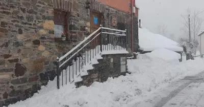a snow covered stairway next to a brick building at Casa Antonio y Benina in Sosas de Laciana