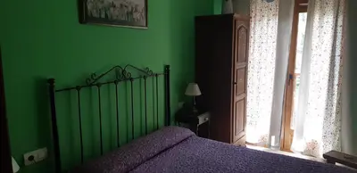 a green bedroom with a bed and a window at Casa Antonio y Benina in Sosas de Laciana