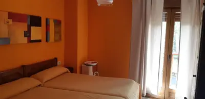 a bedroom with orange walls and a bed and a window at Casa Antonio y Benina in Sosas de Laciana