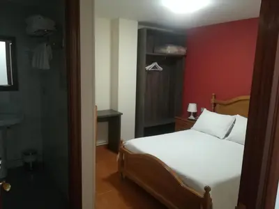 a bedroom with a white bed and a red wall at Pensión Restaurante Casa Camiño II in Palas de Rei