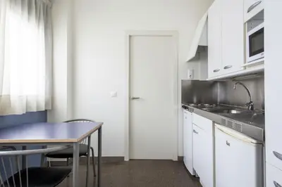 a kitchen with white cabinets and a table at Residencia Universitaria Resa As Burgas in Ourense