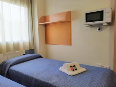 a room with a bed and a tv on the wall at Residencia Universitaria Resa As Burgas in Ourense