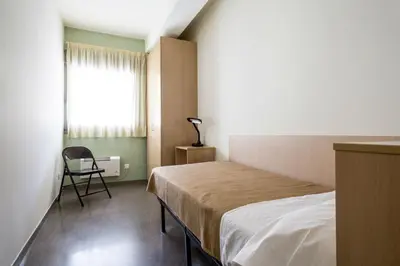 a bedroom with a bed and a window and a chair at Residencia Universitaria Resa As Burgas in Ourense