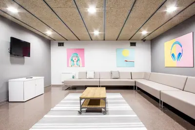 a living room with white furniture and colorful paintings at Residencia Universitaria Resa As Burgas in Ourense