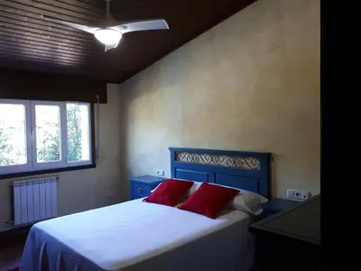a small bedroom with a bed with red pillows at Pension Vilanova in Sigüeiro