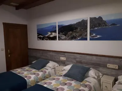 two beds in a room with three pictures on the wall at Pension Vilanova in Sigüeiro