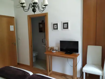 a bedroom with a desk with a television and a chair at Hotel Pazo de Berbetoros in Portomarin