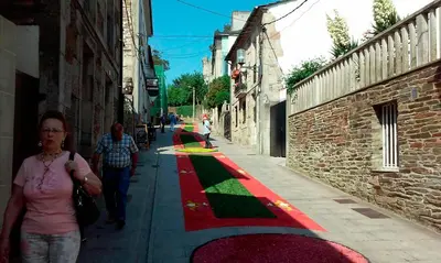 a woman walking down a street with a red and green sidewalk at Pensión y Albergue Matias Locanda in Sarria