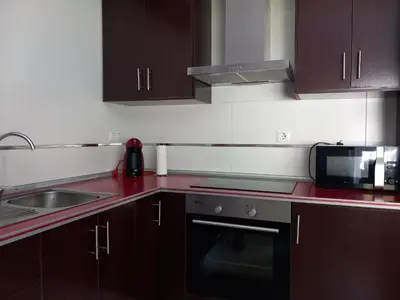 a kitchen with brown cabinets and a sink and a microwave at Viveiro in Viveiro