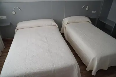 two beds sitting next to each other in a room at Pension Perez in Portomarin