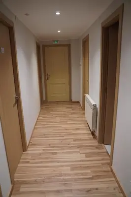 an empty hallway with a yellow door and wooden floors at Pension Perez in Portomarin