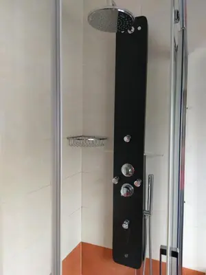 a shower in a bathroom with a black wall at Pension Perez in Portomarin