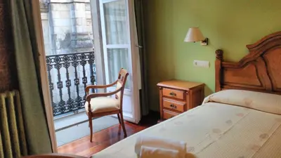 a bedroom with a bed and a chair and a window at PICO SACRO II HOTEL Santiago de Compostela in Santiago de Compostela