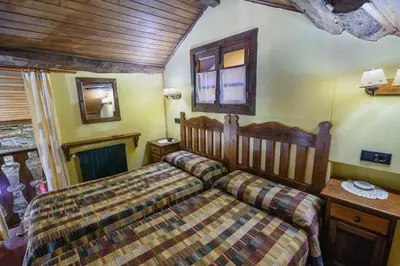 a bedroom with a bed and a table and a window at Apartamentos Casa de Riba in Teijeira